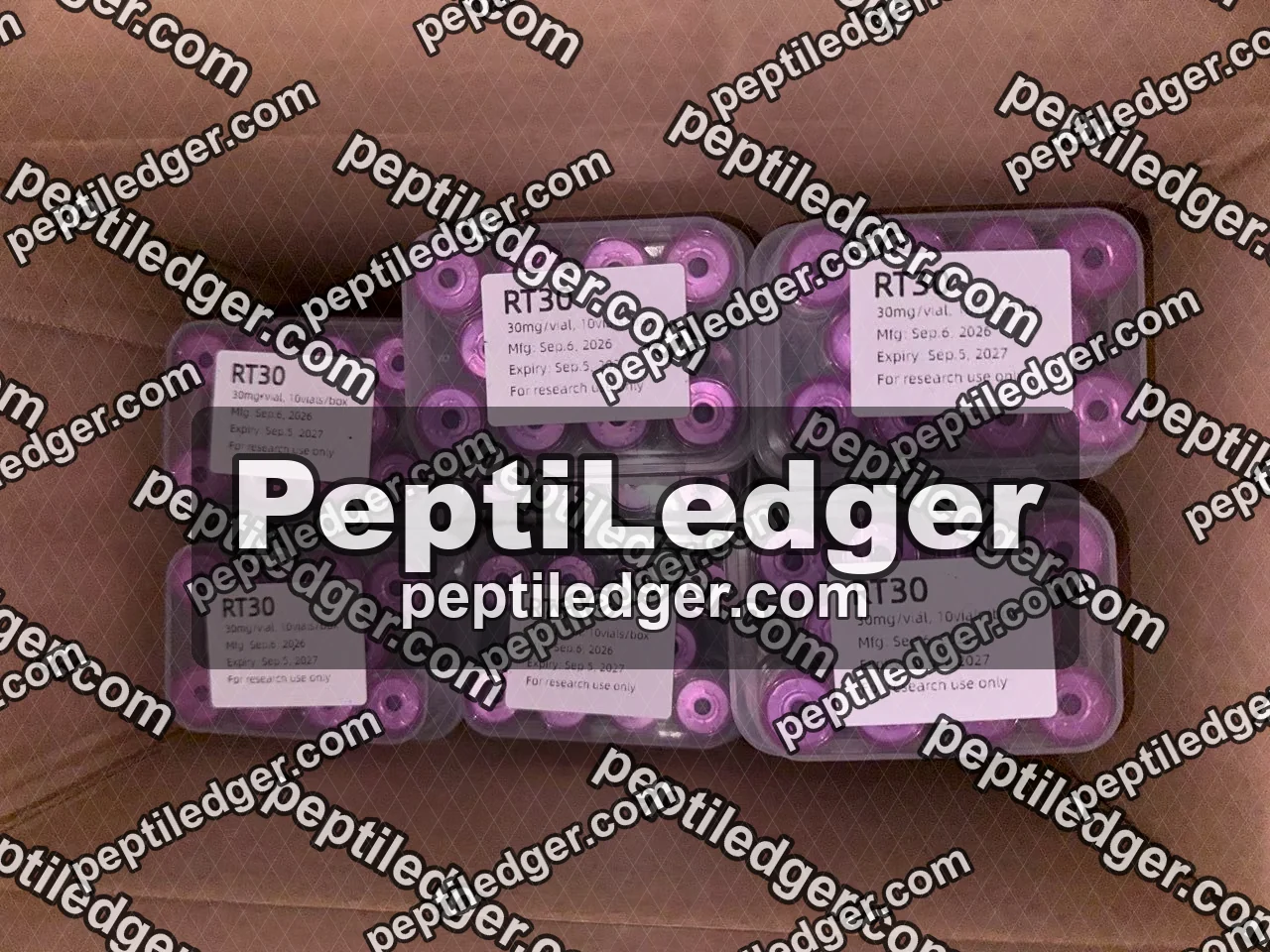 Six clear boxes of pink-capped vials inside a cardboard carton, every lid label reading RT30 with the same manufacture and expiry dates.
